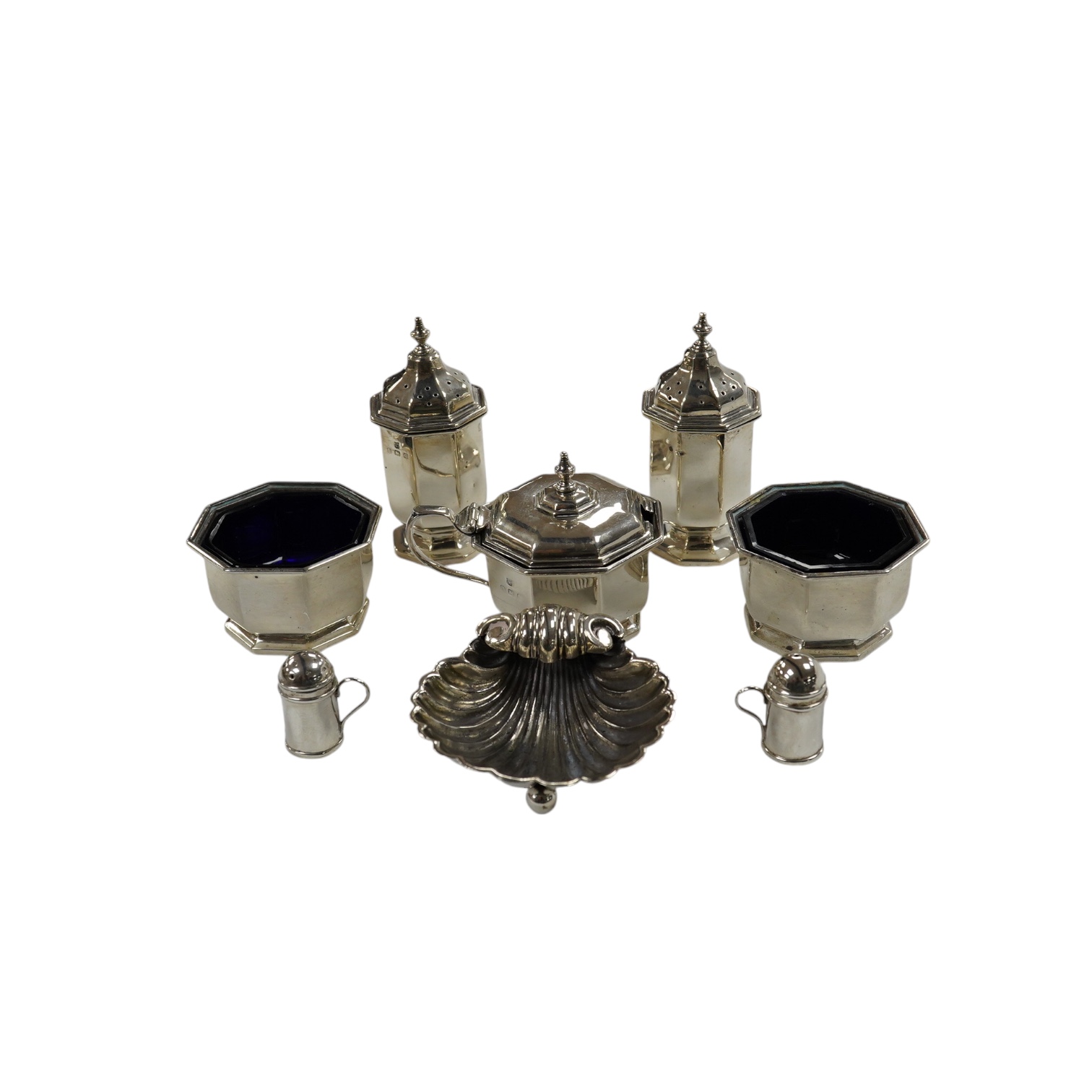 A George V five piece silver condiment set, Birmingham, 1931, two miniature 925 pepperettes and a silver shell salt. Condition - fair